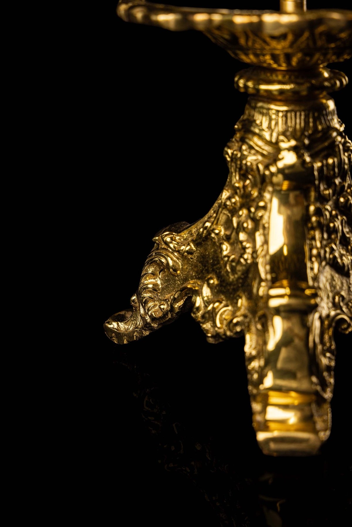 Mosiężny lichtarz liturgiczny, zbliżenie na ornamenty roślinne podstawy i polerowany środkowy element